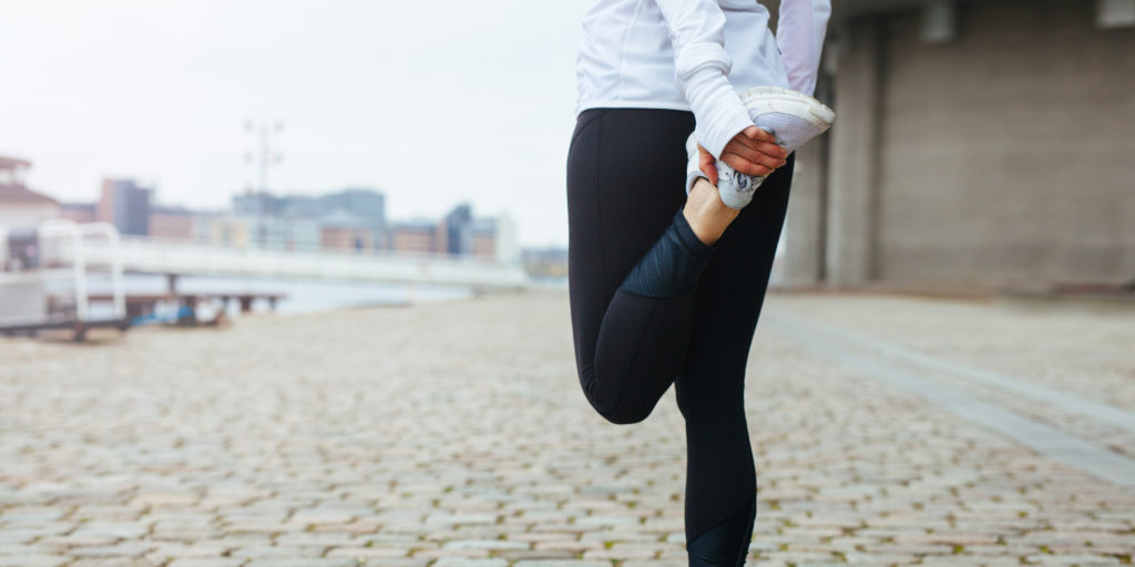 Fit young woman stretching her leg before a run